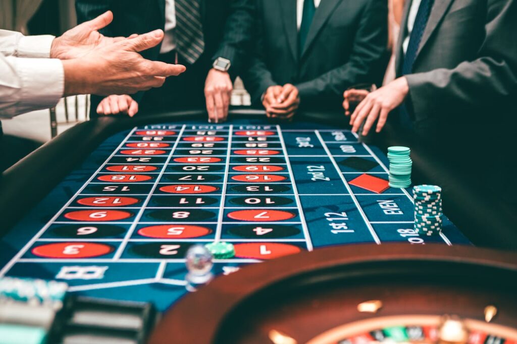 Group of people playing roulette, placing bets in a casino setting.